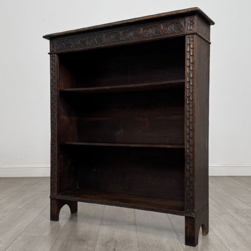 fig 2. A dark brown Victorian carved oak open bookcase with three adjustable shelves and carved decorative borders on the frieze and uprights.