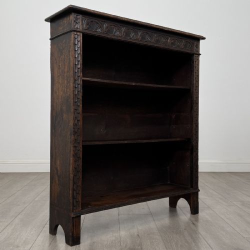 fig 8. A dark brown Victorian carved oak open bookcase with three adjustable shelves and carved decorative borders on the frieze and uprights.