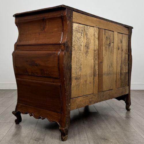 fig 3. An 18th-century French Louis XV bombe commode in warm brown cherrywood featuring ornate brass handles and cabriole legs.