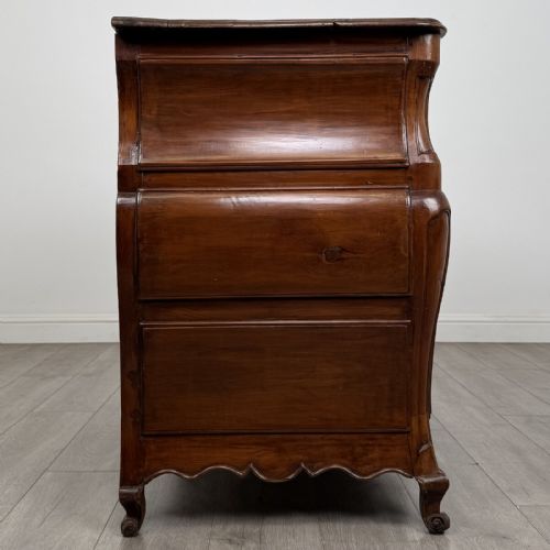 fig 6. An 18th-century French Louis XV bombe commode in warm brown cherrywood featuring ornate brass handles and cabriole legs.