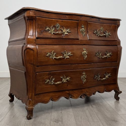 fig 7. An 18th-century French Louis XV bombe commode in warm brown cherrywood featuring ornate brass handles and cabriole legs.