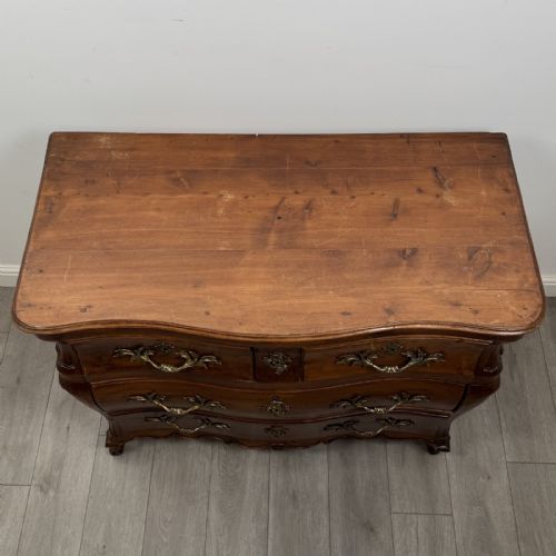 fig 8. An 18th-century French Louis XV bombe commode in warm brown cherrywood featuring ornate brass handles and cabriole legs.