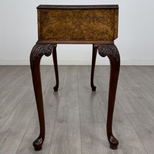 fig 2. An antique burr walnut writing table featuring three drawers, carved cabriole legs, and decorative brass handles.