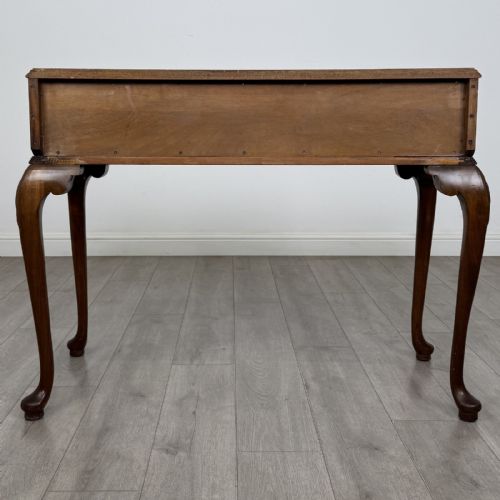 fig 4. An antique burr walnut writing table featuring three drawers, carved cabriole legs, and decorative brass handles.