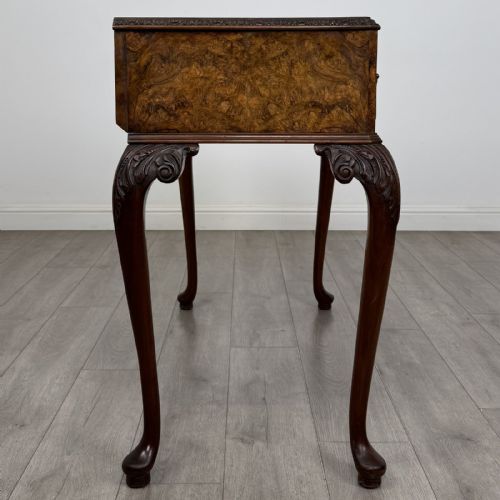 fig 6. An antique burr walnut writing table featuring three drawers, carved cabriole legs, and decorative brass handles.