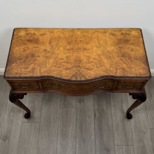 fig 8. An antique burr walnut writing table featuring three drawers, carved cabriole legs, and decorative brass handles.