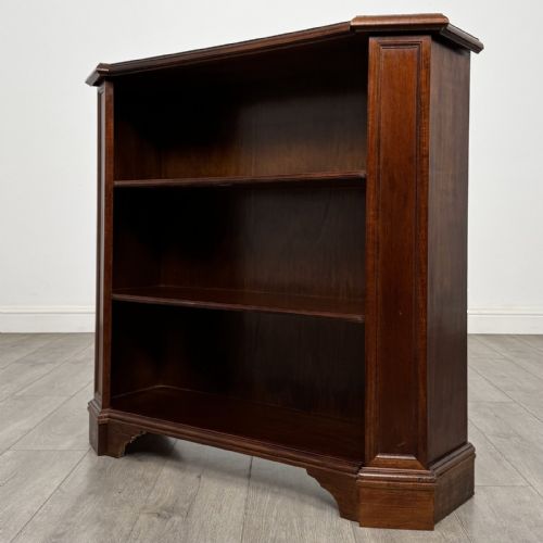 fig 2. An antique mahogany low open bookcase featuring canted corner posts, three tiers of open shelving, and a shaped bracket foot base.