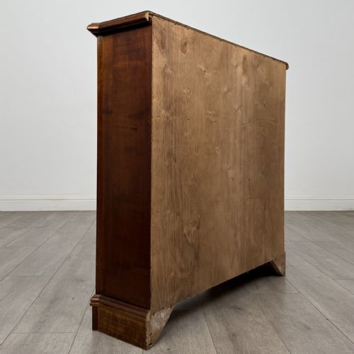 fig 4. An antique mahogany low open bookcase featuring canted corner posts, three tiers of open shelving, and a shaped bracket foot base.