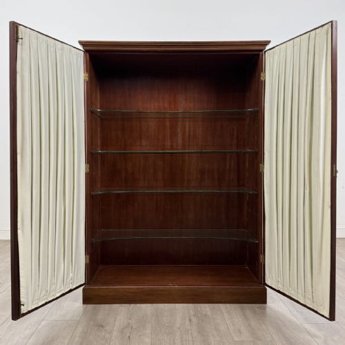 fig 1. A Georgian style dark mahogany display cabinet featuring two glazed doors with geometric astragal glazing bars and interior green silk lining.