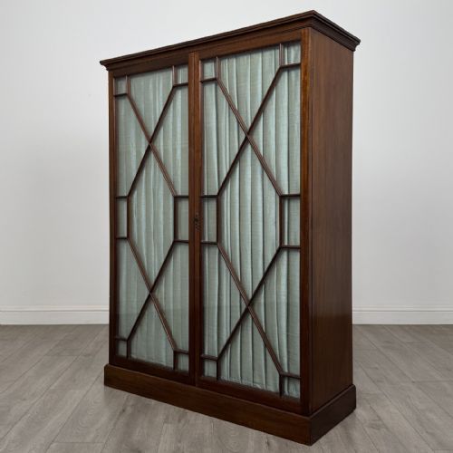 fig 2. A Georgian style dark mahogany display cabinet featuring two glazed doors with geometric astragal glazing bars and interior green silk lining.