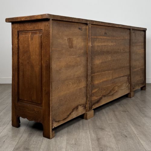 fig 4. A wide medium brown oak sideboard featuring four arched panel doors, two central drawers, decorative metal hardware, and a shaped apron.