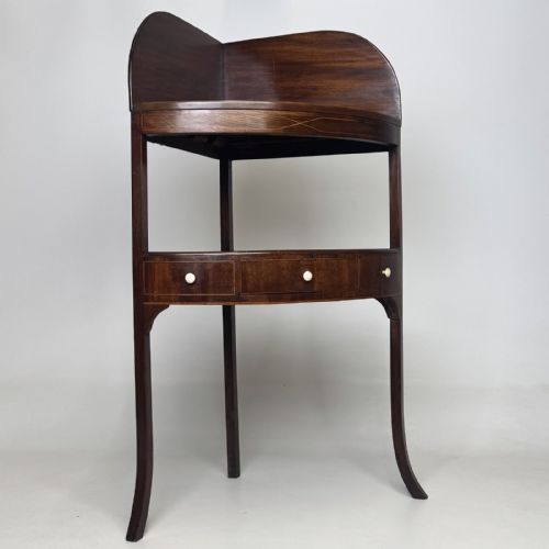 fig 3. A Georgian style mahogany corner stand featuring a curved raised gallery, inlaid drawer, white handles, and slender splayed legs.