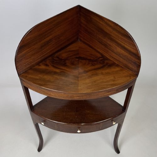 fig 4. A Georgian style mahogany corner stand featuring a curved raised gallery, inlaid drawer, white handles, and slender splayed legs.