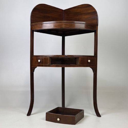 fig 5. A Georgian style mahogany corner stand featuring a curved raised gallery, inlaid drawer, white handles, and slender splayed legs.