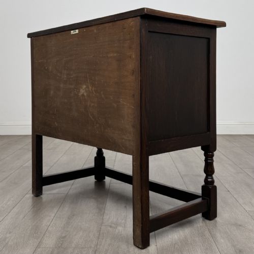 fig 6. A dark brown oak antique cupboard featuring a carved top drawer, panelled double doors with carved diamond motifs, and turned legs with stretchers.