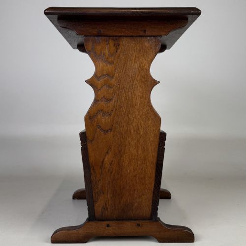 fig 2. A dark brown oak side table featuring a flat rectangular top supported by shaped vertical legs and a lower integrated magazine compartment.