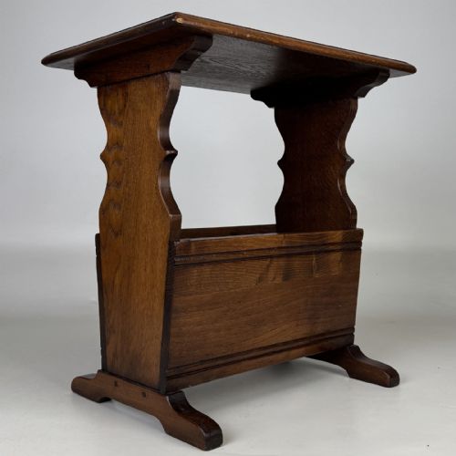 fig 3. A dark brown oak side table featuring a flat rectangular top supported by shaped vertical legs and a lower integrated magazine compartment.