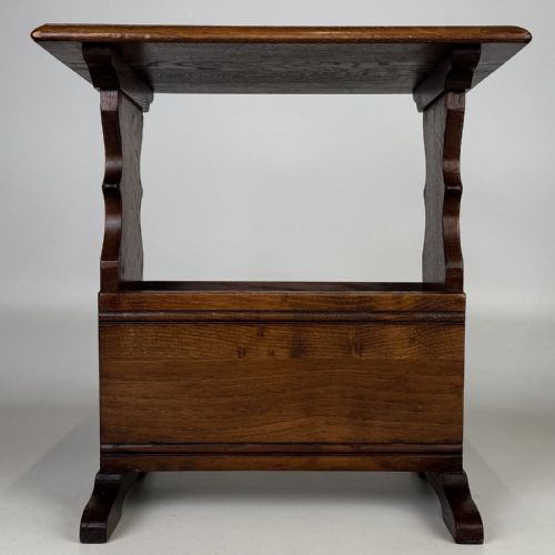 fig 4. A dark brown oak side table featuring a flat rectangular top supported by shaped vertical legs and a lower integrated magazine compartment.
