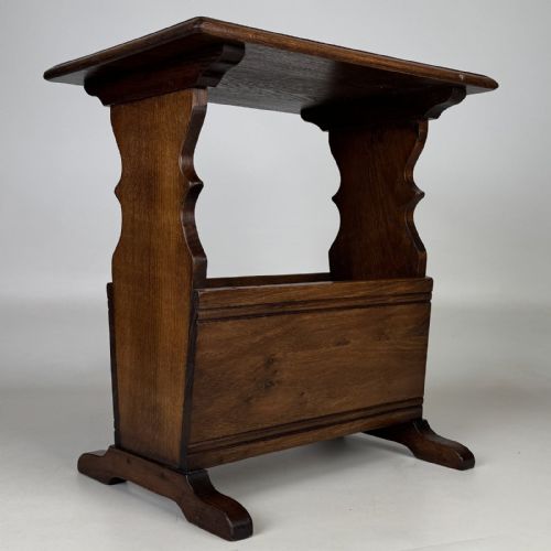 fig 7. A dark brown oak side table featuring a flat rectangular top supported by shaped vertical legs and a lower integrated magazine compartment.