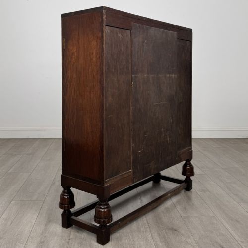 fig 4. A dark oak fitted bureau featuring a central slant-front writing slope over three drawers, flanked by two side cupboard doors and supported on turned feet with lower stretchers.