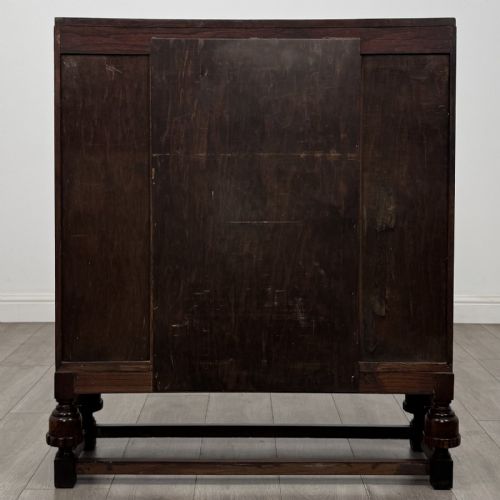 fig 5. A dark oak fitted bureau featuring a central slant-front writing slope over three drawers, flanked by two side cupboard doors and supported on turned feet with lower stretchers.