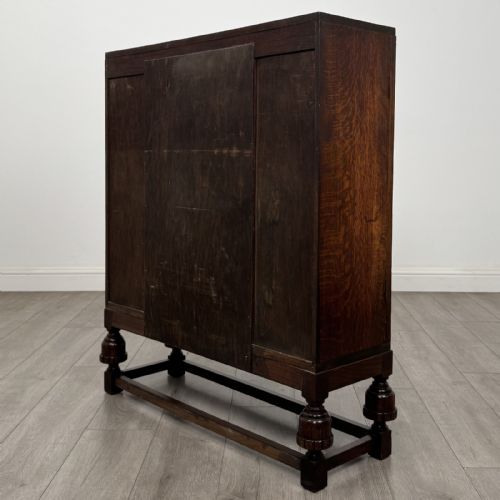 fig 6. A dark oak fitted bureau featuring a central slant-front writing slope over three drawers, flanked by two side cupboard doors and supported on turned feet with lower stretchers.