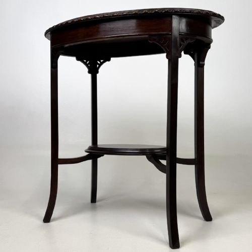 fig 1. An Edwardian oval mahogany side table featuring a carved gadrooned top edge, pierced corner brackets, slender tapered legs, and a lower oval shelf.