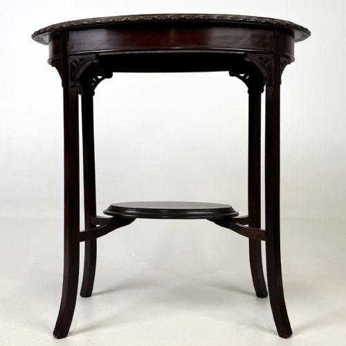 fig 4. An Edwardian oval mahogany side table featuring a carved gadrooned top edge, pierced corner brackets, slender tapered legs, and a lower oval shelf.