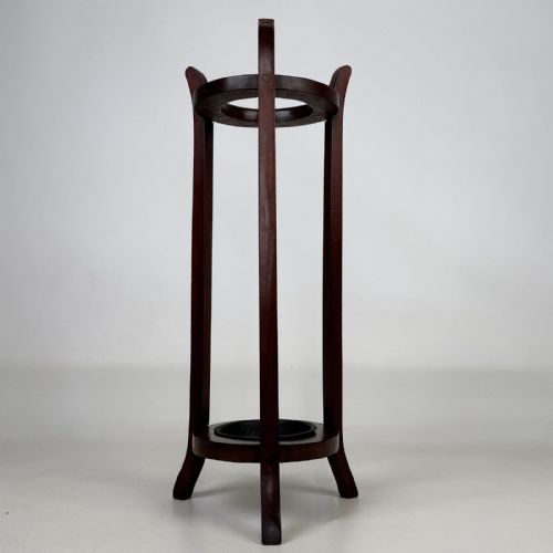 fig 2. A tall, dark mahogany three-legged umbrella stand featuring a circular top ring and a metal drip tray built into the lower ring base.