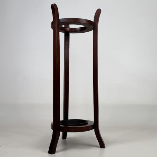 fig 3. A tall, dark mahogany three-legged umbrella stand featuring a circular top ring and a metal drip tray built into the lower ring base.
