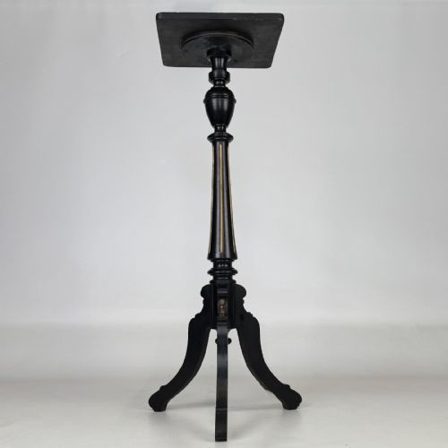 fig 2. A tall Victorian ebonised wooden plant stand featuring a square top, turned fluted column with gilt highlights, and a curved tripod base.