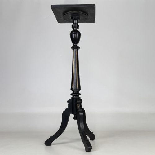 fig 4. A tall Victorian ebonised wooden plant stand featuring a square top, turned fluted column with gilt highlights, and a curved tripod base.