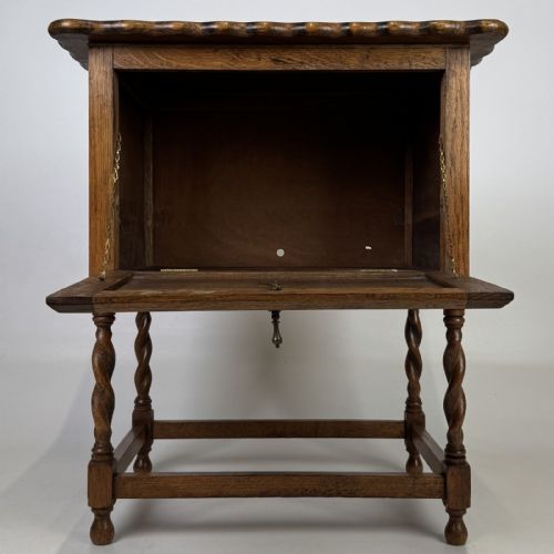 fig 1. An Edwardian oak side cabinet featuring a single panelled door, a scalloped edge top, and four barley twist legs joined by a lower stretcher.