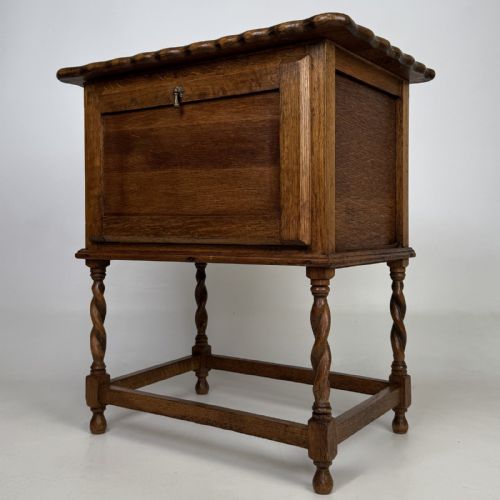 fig 2. An Edwardian oak side cabinet featuring a single panelled door, a scalloped edge top, and four barley twist legs joined by a lower stretcher.