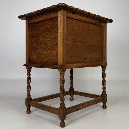 fig 4. An Edwardian oak side cabinet featuring a single panelled door, a scalloped edge top, and four barley twist legs joined by a lower stretcher.
