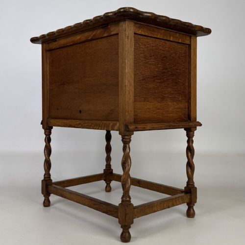 fig 6. An Edwardian oak side cabinet featuring a single panelled door, a scalloped edge top, and four barley twist legs joined by a lower stretcher.