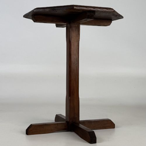 fig 2. An antique dark oak side table featuring an octagonal top, a central chamfered pedestal, and a four-point cruciform base.