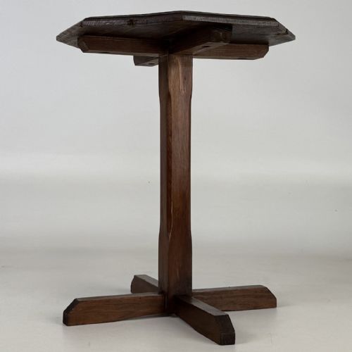 fig 4. An antique dark oak side table featuring an octagonal top, a central chamfered pedestal, and a four-point cruciform base.