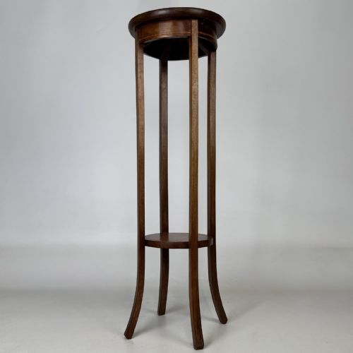 fig 1. A tall Edwardian mahogany plant stand featuring a circular top, long slender legs, and a small circular lower shelf.