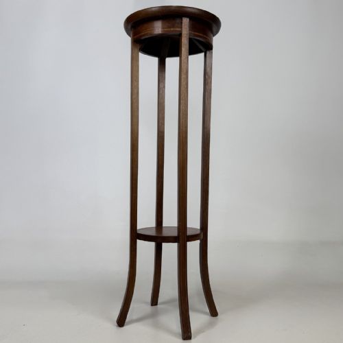 fig 3. A tall Edwardian mahogany plant stand featuring a circular top, long slender legs, and a small circular lower shelf.