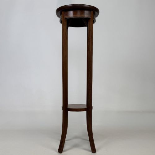 fig 4. A tall Edwardian mahogany plant stand featuring a circular top, long slender legs, and a small circular lower shelf.