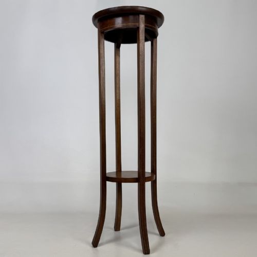 fig 5. A tall Edwardian mahogany plant stand featuring a circular top, long slender legs, and a small circular lower shelf.