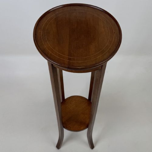 fig 6. A tall Edwardian mahogany plant stand featuring a circular top, long slender legs, and a small circular lower shelf.