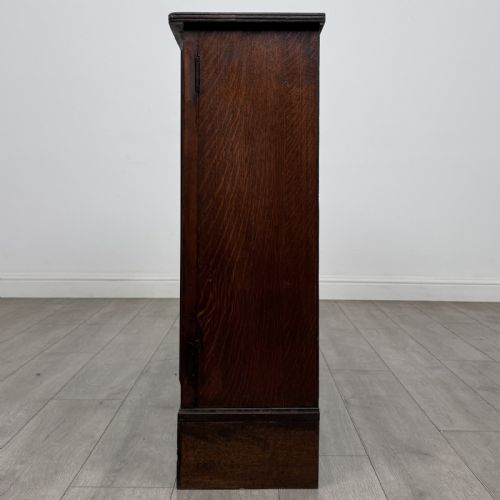 fig 4. A low Victorian dark oak display cabinet featuring two glazed doors, turned wooden knobs, bracket feet, and a single interior shelf trimmed with scalloped leather.