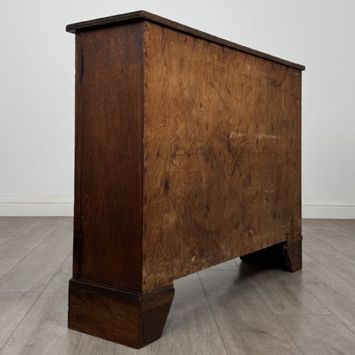 fig 5. A low Victorian dark oak display cabinet featuring two glazed doors, turned wooden knobs, bracket feet, and a single interior shelf trimmed with scalloped leather.