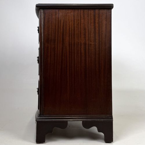 fig 2. A dark mahogany small chest of three drawers featuring brass ring pull handles and bracket feet.