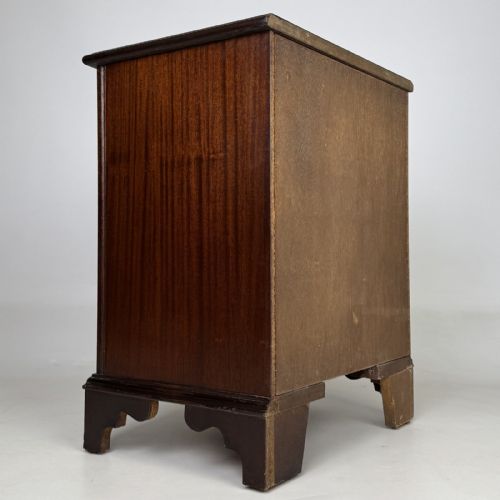 fig 3. A dark mahogany small chest of three drawers featuring brass ring pull handles and bracket feet.