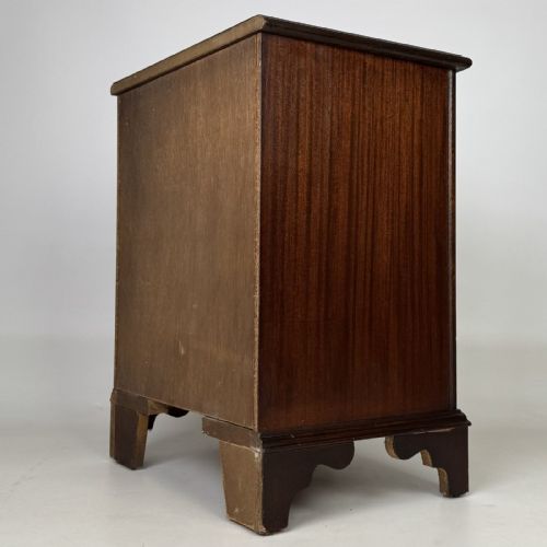 fig 5. A dark mahogany small chest of three drawers featuring brass ring pull handles and bracket feet.