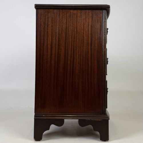 fig 6. A dark mahogany small chest of three drawers featuring brass ring pull handles and bracket feet.