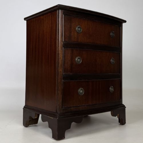 fig 7. A dark mahogany small chest of three drawers featuring brass ring pull handles and bracket feet.